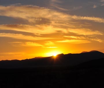 Photo of a golden sunset reflecting on clouds over the Little Hatchet Mountains