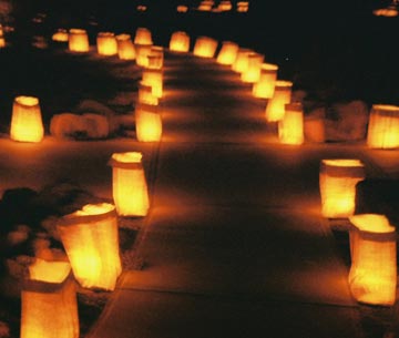 Photo of bright candlelit luminarias lining both sides of a dark path